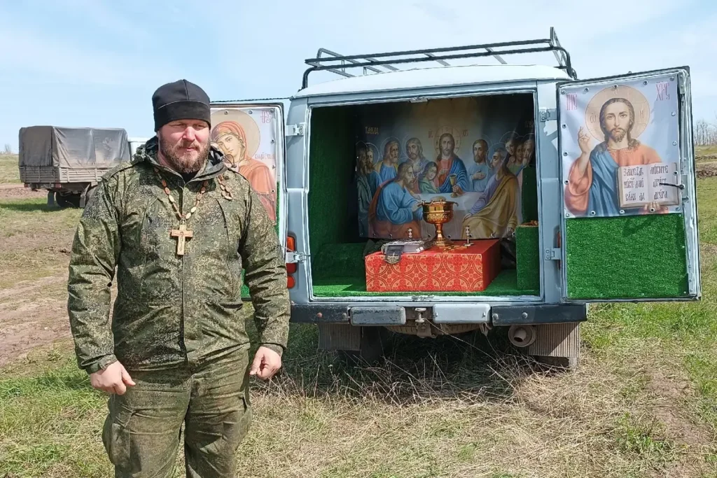 Священник Роман Чебоненко стоит рядом с полевым «храмом-буханкой». Фото вместе с постом выложено 6 октября 2023 года, в котором священник благодарит за закрытие денежного сбора на покупку нового УАЗа для полевого храма. Источник: личная страница Чебоненко в ВКонтакте.