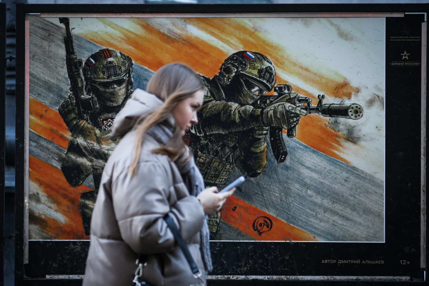 Девушка проходит мимо плаката с изображением российских военнослужащих на уличной выставке в Санкт-Петербурге